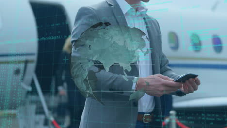 animación de un globo giratorio y procesamiento de datos, sobre un hombre de negocios que usa un teléfono inteligente junto al avión