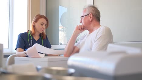female doctor analyzes electrocardiogram displayed on digital tablet. cardiologist compares online and paper medical records at table in clinic
