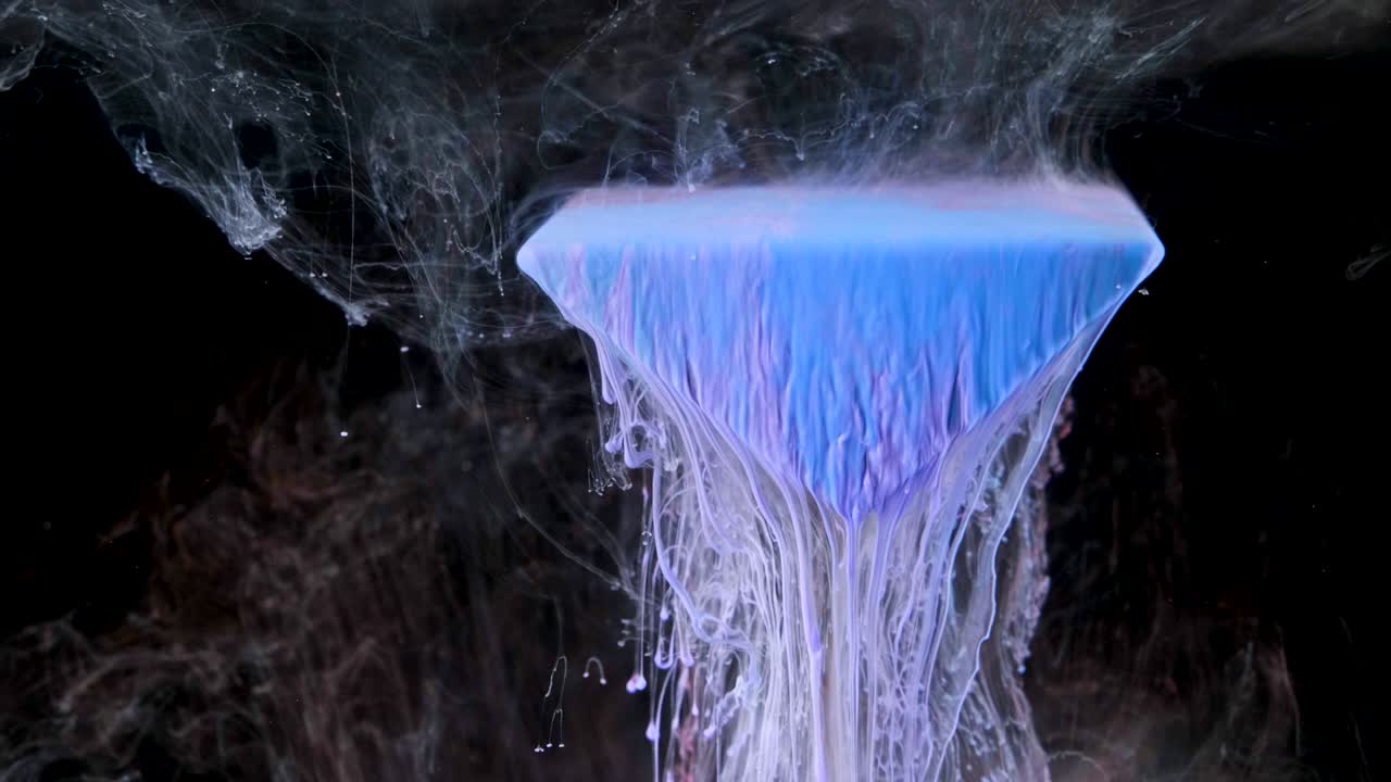 다채로운 잉크 페인트가 물 에 있는 프리스마에서 천천히 흘러나옵니다.