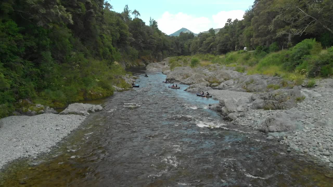 la gente rema en kayak por el rápido con rocas en el hermoso y prístino río azul claro pelours, nueva zelanda - drone aéreo