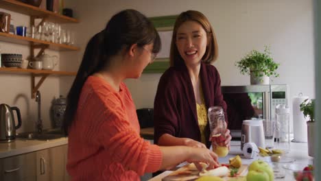 아시아 어머니 와 딸 은 미소 짓는 부 ⁇  에서 건강 한 음료 를 준비 하고 있다