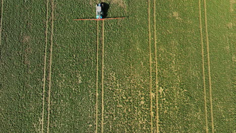 aerial top down shot of tractor spraying liquid manure on farm field during sunny day in spring