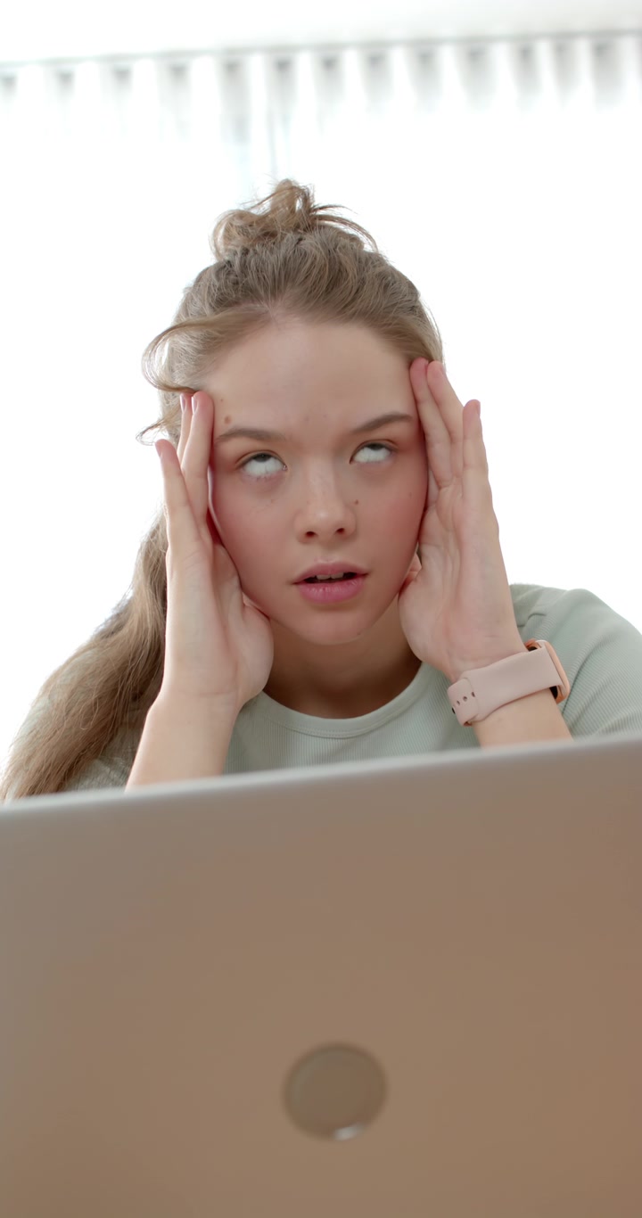 Vertical video: Laptop stressing woman, pressing temples, massaging neck, seeking calm at home desk