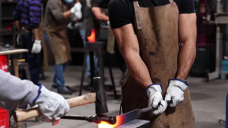 blacksmiths making iron instrument with hammer