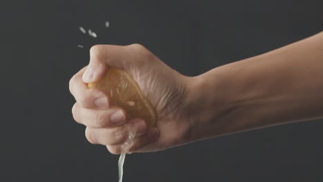 hand squeezes a half fresh lemon