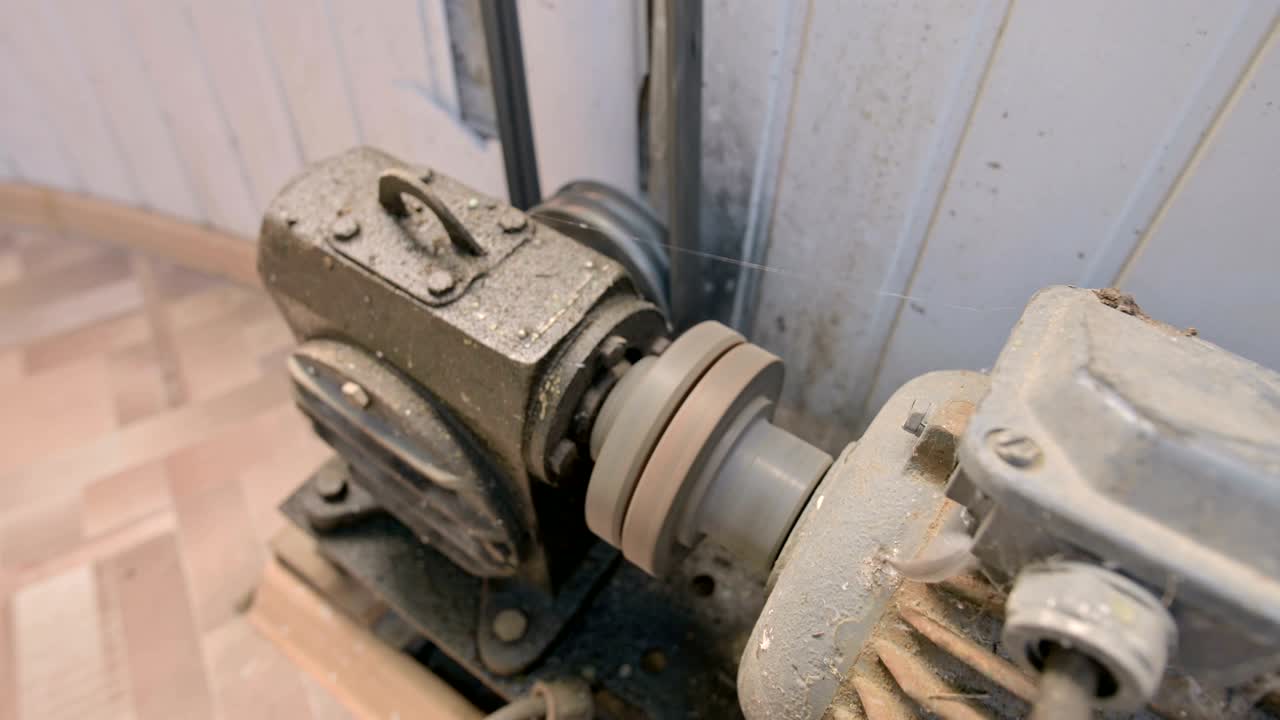 먼지와 으로 인 오래된 전기 모터는 벨트 드라이브를 가진 카르단 기어 박스를 통해 두 개의 스레드 리를 다른 메커니즘으로 회전시니다.