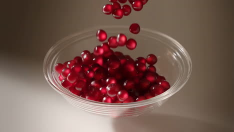 pomegranate seeds falling into a clear glass bowl