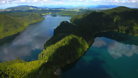 aerial over two lakes and a forest with rolling hills in the distance on a partly cloudy day