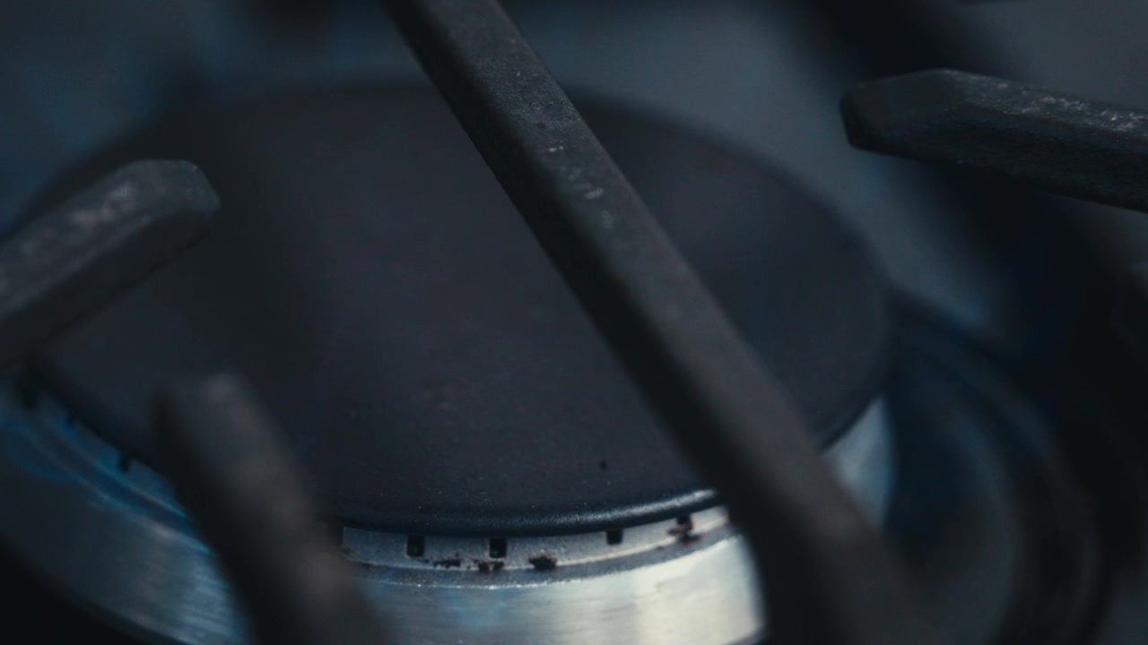 Extreme close-up of cast iron gas stove burner in dark cinematic light
