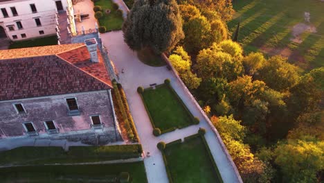 aerial view over a medieval castle on top of a hill, surrounded by vineyards, in italy, at sunrise