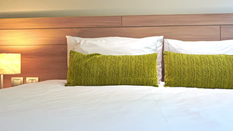 panning shot of cushions and pillows on bed in hotel bedroom