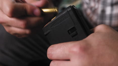 man loading ar 15 ammo in to a magazine