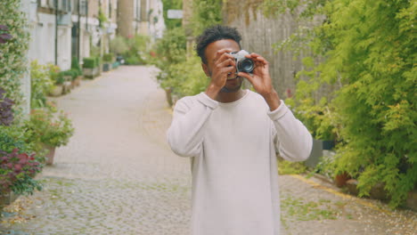 young man in city taking photo on digital camera to post to social media