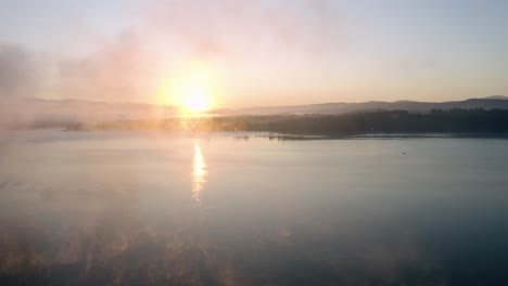 Amanecer-En-Un-Lago-Con-Colores-Asombrosos,-Una-Niebla-Flotando-Sobre-Una-Superficie-De-Agua