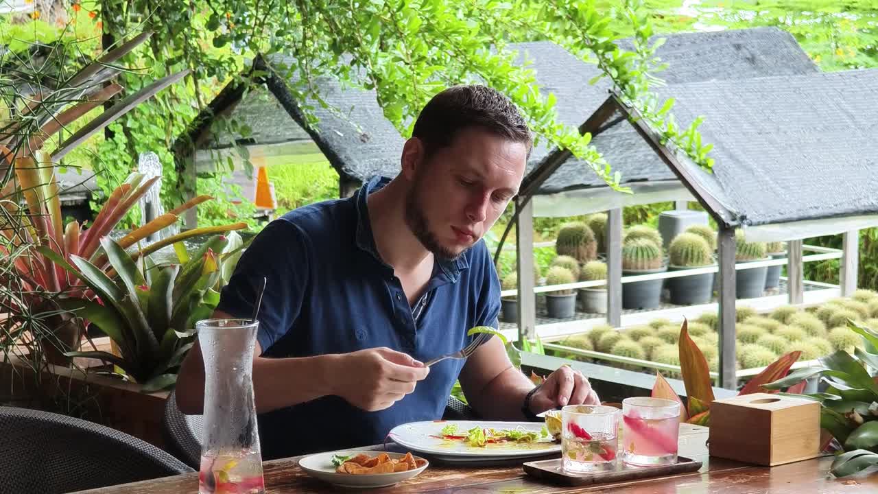 hombre disfrutando de una comida en un restaurante de jardín tropical