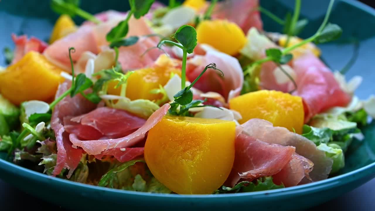 Frisk salat med blandet grønt, kjøtt og frukt servert i en bolle. En bolle inneholder en salat med salat, kjøtt, frukt og nøtter, klar til å spises.