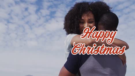 Animation-of-christmas-greetings-text-over-diverse-couple-on-beach