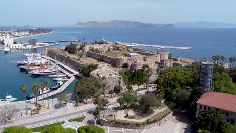 Cinematic-aerial-shot-approaching-harbor-and-ancient-castle-in-greek-island-during-sunny-day