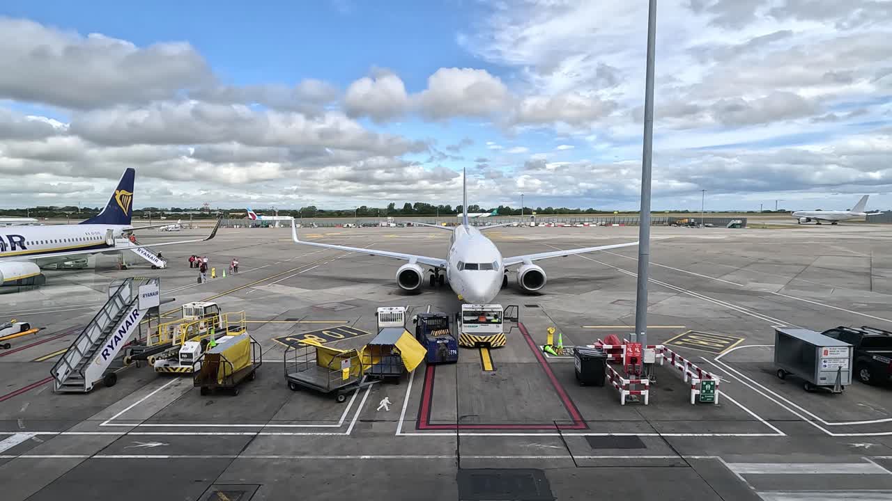 Plane on tarmac at Dublin Airport surrounded by ground crew equipment under a bright sky