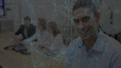 Man working at office desk using laptop, charting network-graph overlay for technology analysis