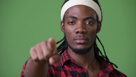 young handsome african man with dreadlocks against green background