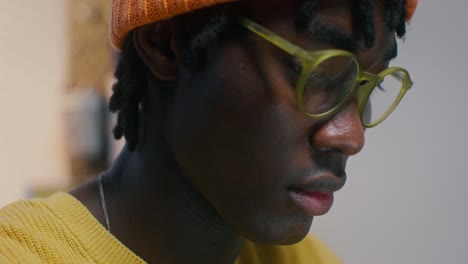 close-up portrait of a young person wearing glasses and an orange beanie