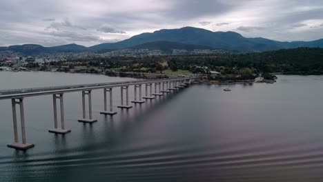 backward shot of bridge standing still on a river with range of mountains at background