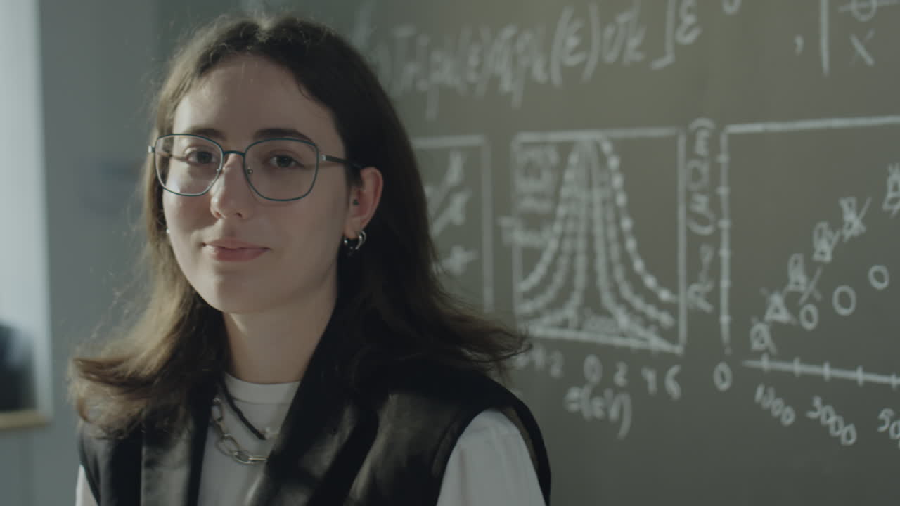 Young Woman in Glasses Against a Chalkboard with Scientific Formulas