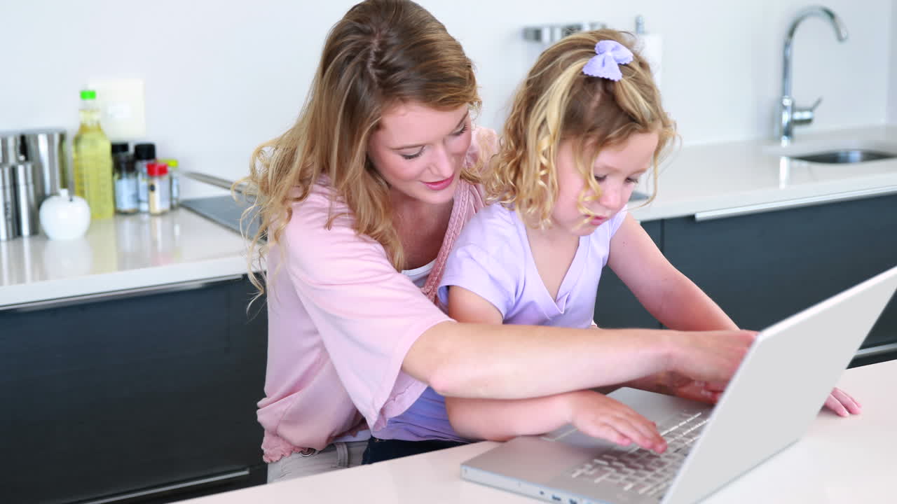Pretty mother and daughter using laptop together