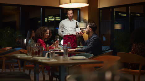 un camarero sirviendo a una pareja romántica en un restaurante. un sommelier sosteniendo una botella de vino.