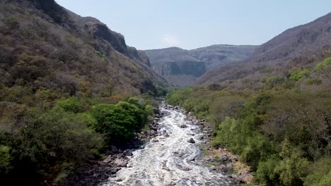 drone aéreo siguiendo lentamente un río en un cañón en el parque nacional barranca de huentitan en méxico