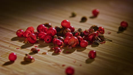 a pile of pink peppercorn on a wooden surface with dramatic lighting, camera orbiting