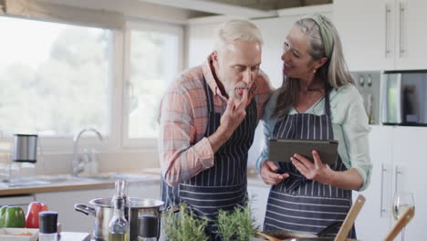 Pareja-Caucásica-De-Mediana-Edad-Usando-Tableta,-Preparando-Comida,-Cocinando-En-La-Cocina-De-Casa,-Cámara-Lenta