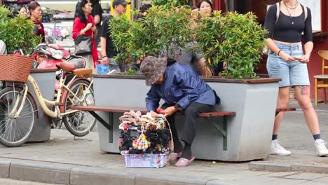 old person selling souvenirs in hanoi, vietnam