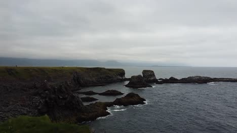 Ascending-aerial-shot-of-rocky-coastline-and-shoreline-in-iceland-with-clouds-at-sky