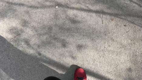 Füße-Mit-Roten-Schuhen,-Die-An-Einem-Sonnigen-Tag-Auf-Grauem-Asphalt-Gehen-Pov