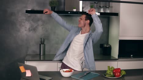 Active-caucasian-young-man-enjoying-funny-dance-standing-in-modern-grey-coloured-kitchen,-happy-funky-independent-guy-dancing