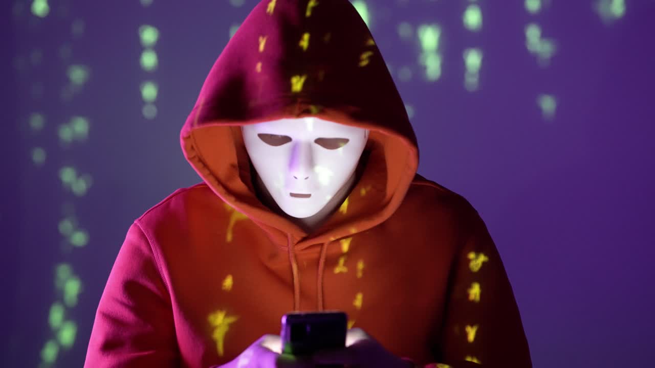 Hooded figure in a white mask uses a smartphone under projected green code, symbolizing cyber surveillance, privacy risks, hacking culture, digital secrecy, and information breach in the dark net