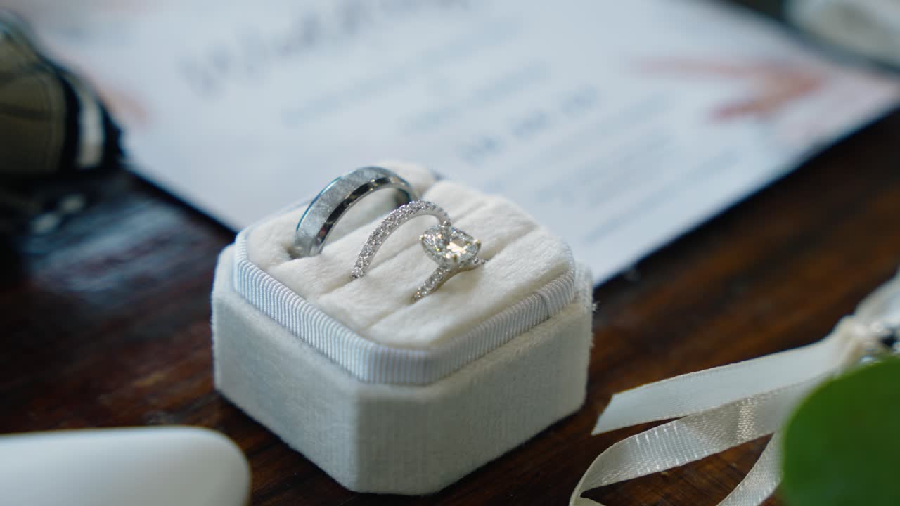 A close-up detail shot of the bride and groom's wedding rings in a velvet box, filmed with a slow push-in movement. Captured at a fall wedding in South Georgia at a rustic winery setting.