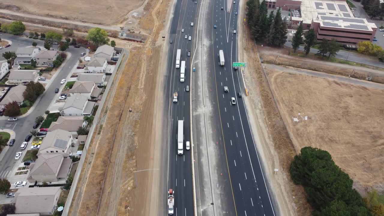 Forward and upward moving areal drone footage looking down at a busy highway, freeway