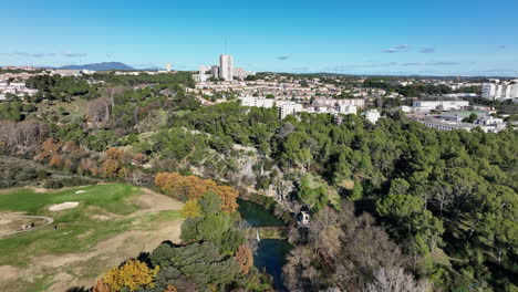 sunny-day-flight-over-Golf-Montpellier-Fontcaude,-transitioning-to-the-vibrant-l