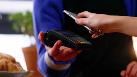 woman paying bill through smartphone using nfc technology