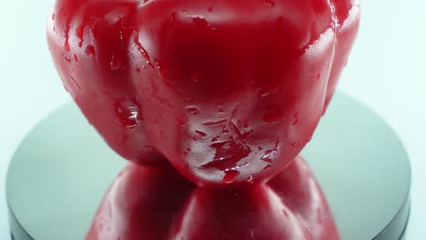 a close up shot of a sweet red wet pepper on a reflecting rotating stand 360, slow motion, 4k video