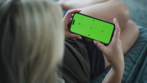 woman using a smartphone with a green screen