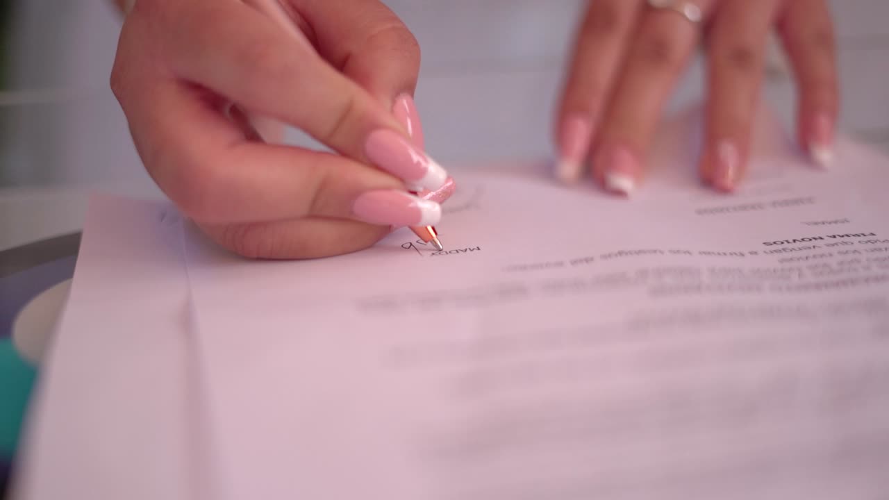 Close-up of Hands Signing a Document