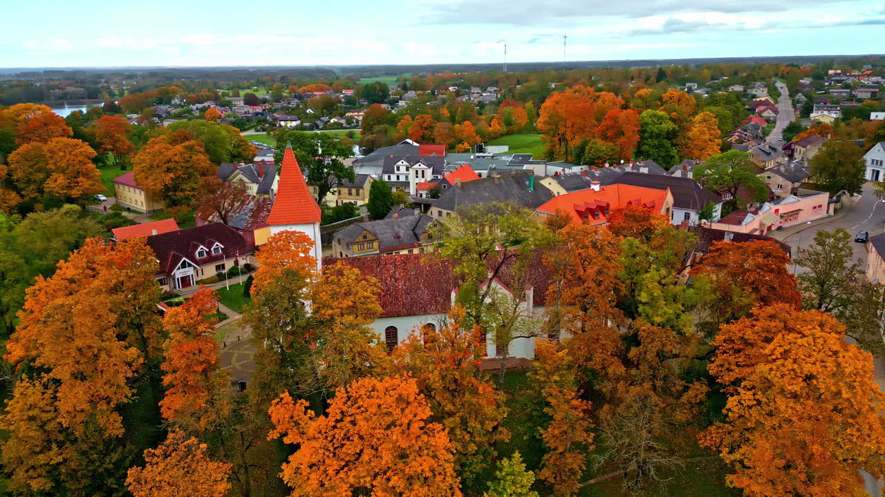 Talsu church in latvia surrounded by vibrant autumn trees and scenic townscape, aerial view
