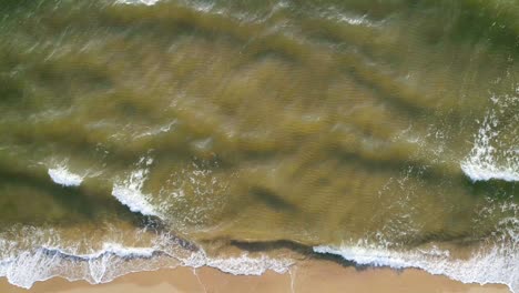 tropical beach aerial view, top view of waves break on tropical white sand beach. sea waves seamless loop on the beautiful sand beach.