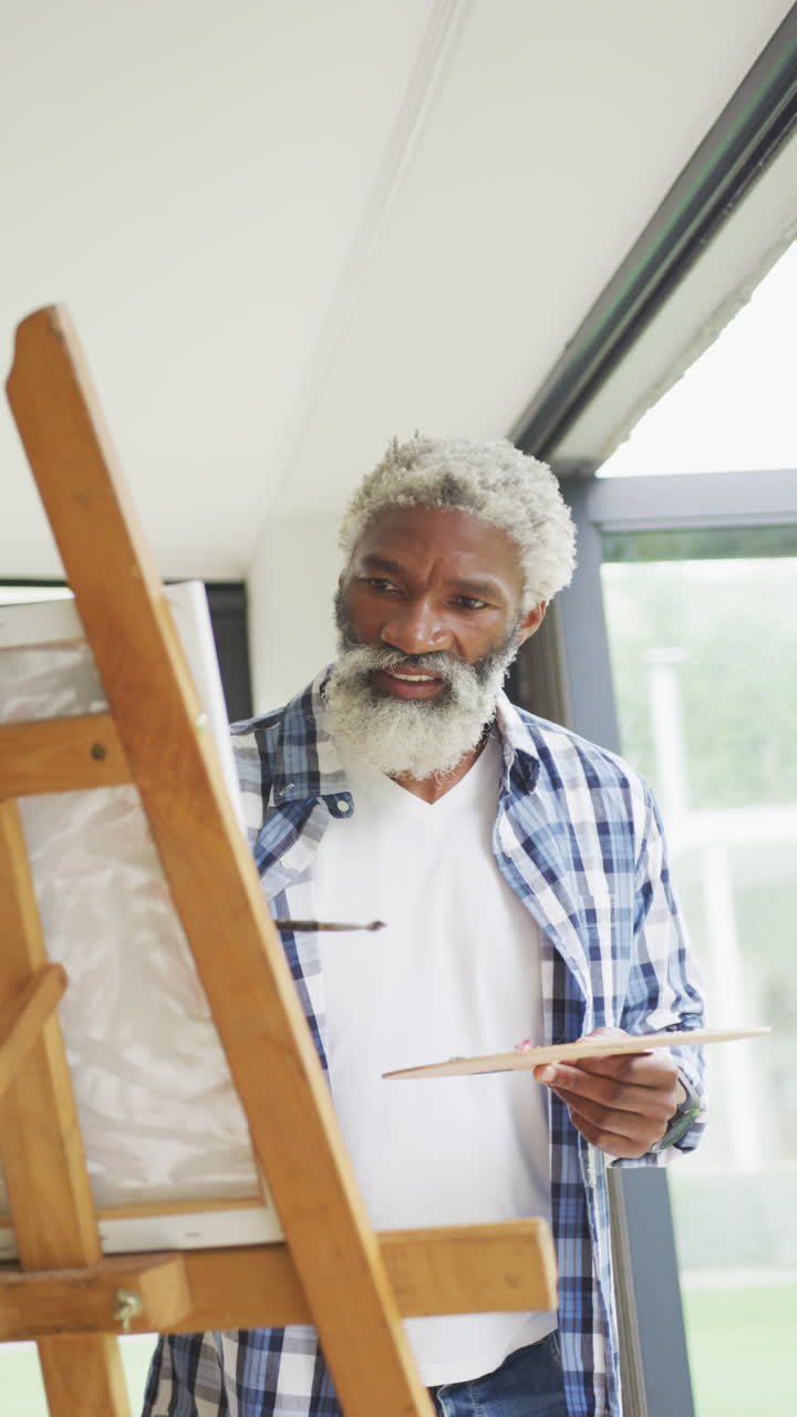 video vertical de un anciano afroamericano que pinta en su casa