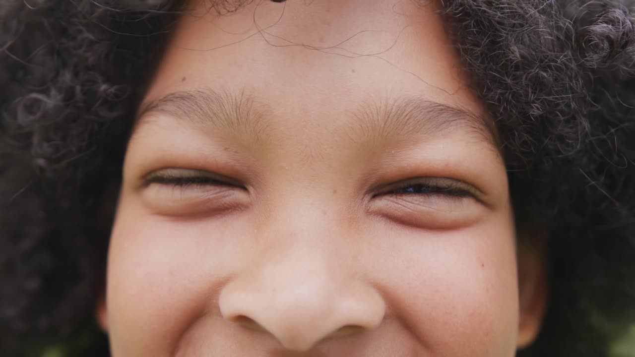 Video portrait close up of eyes of smiling biracial schoolgirl with afro hair