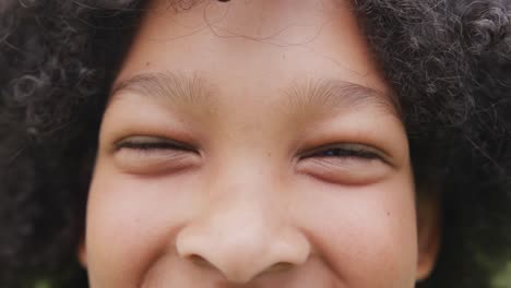 video portrait close up of eyes of smiling biracial schoolgirl with afro hair